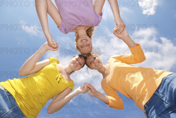 Group of three friends smiling with heads together looking at camera. Low angle view