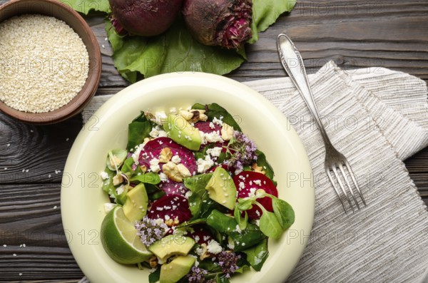 Top view at mediterranean roasted beet salad with avocado walnuts feta cheese oregano and mash leaves on dinner table