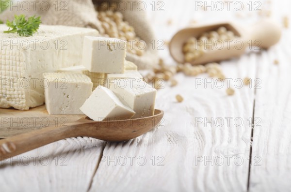 Soy Bean curd tofu on cutting board and in hemp sack on white wooden kitchen table. Space for text
