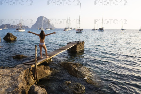 Ibiza cala d Hort girl on pier sunset Es Vedra islet Balearic Islands