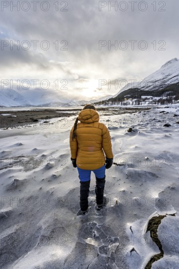 A woman in winter clothing on the frozen shore of the Ullsfjord, Sjursnes, Tromso, Troms, Norway, Europe