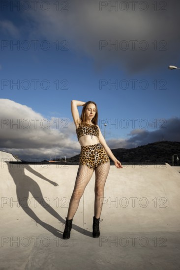 Vertical portrait of a young Caucasian woman with armpit hair dancing urban dance in the street in summertime