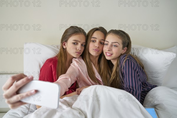 Pajama party best friend girls selfie at bed with tablet and smartphone