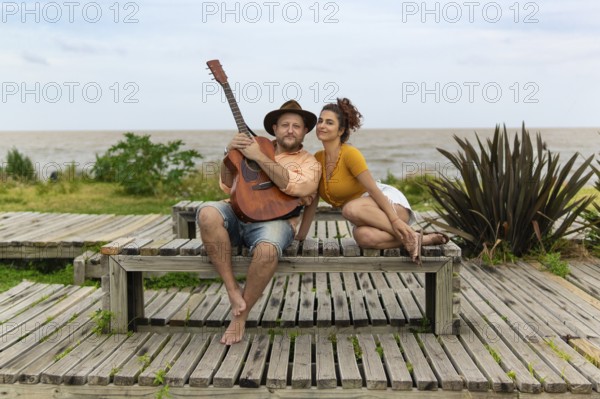 Couple of musicians sitting on the beach looking at the camera