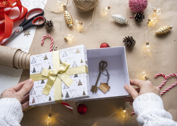 Key to house with keychain on cozy home in gift box with Christmas decor packaging. Pack present for New Year, Christmas. Building, project, moving to new house, mortgage, rent, purchase real estate