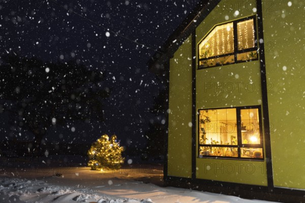 Cozy festive window of the house outside with the warm light of fairy lights garlands inside, celebrate Christmas and New Year in a warm home. Christmas tree, bokeh, snow on pine trees and snowfall