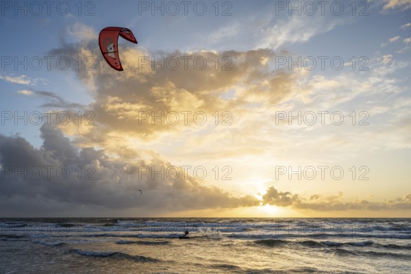 A kitesurfer in the distance at sunset over the sea, impressive cloud formations, Texel