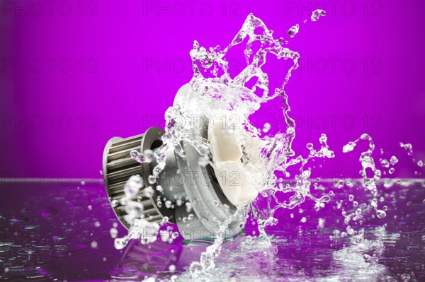 Auto parts, engine cooling pump in spurts of water on purple gradient background