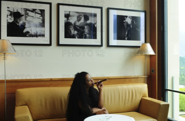 A Brazilian woman enjoys smoking a cigar in the Miles Davis Smoker's Lounge of the Kulm hotel in St. Moritz