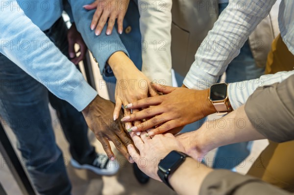 Coworkers joining hands in unity, symbolizing teamwork and collaboration in a modern coworking office environment