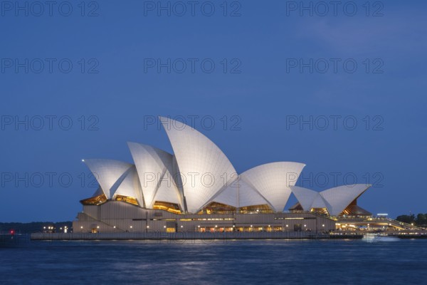 Illuminated Sydney Opera House at night train blue hour, surrounded by water, with unique architecture and vibrant atmosphere, Sydney, Australia