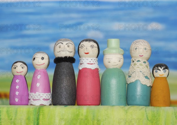 Seven funny painted wooden cones man and woman, big and small in front of a colourful painted background, North Rhine-Westphalia, Germany