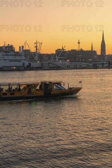A ship on a river at sunset with the city silhouette in the background, Hamburg, Germany