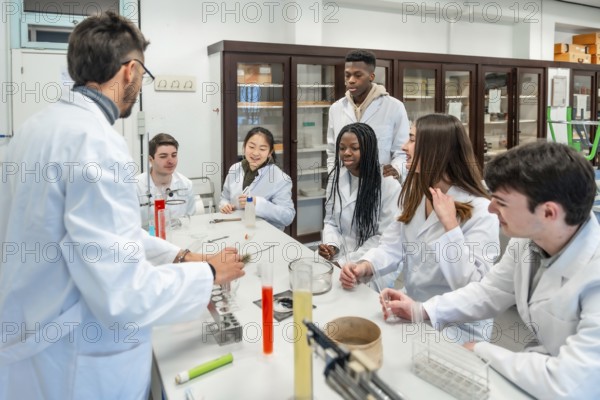 Multi ethnic university students wearing lab coats listening to their chemistry teacher explaining a scientific experiment in a school laboratory