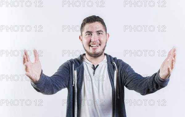 Friendly young man welcoming with open arms isolated. Hospitable guy opening arms to the camera