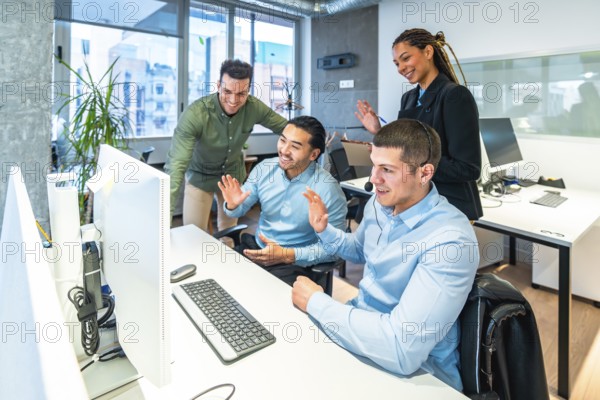 Business colleagues waving enthusiastically at the computer during an engaging video call in a bright, modern office environment