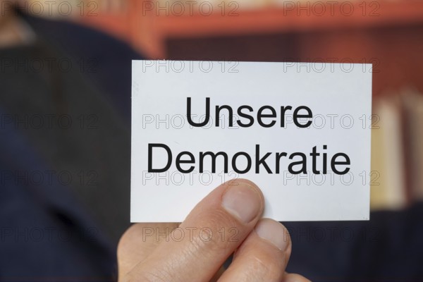 Man showing a business card with (added text) OUR DEMOCRACY (symbolic image)
