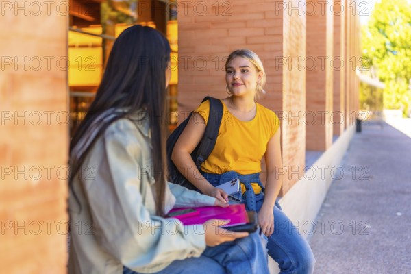 Multi-ethnic female chinese and caucasian friends sitting and talking at the university campus