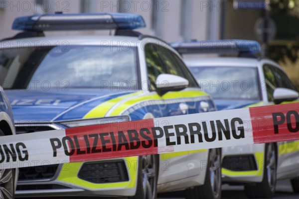 (Photomontage) Symbolic image of a police operation: police cordon in front of an emergency vehicle