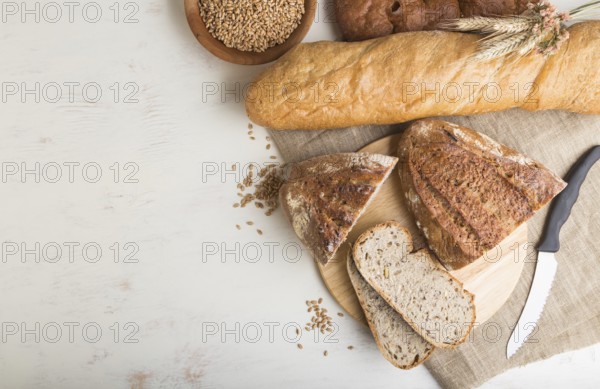 Sliced bread with different kinds of fresh baked bread on a white wooden background. top view, flat lay, copy space