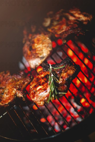 From above of delicious appetizing meat steaks with fresh rosemary grilling on rack above burning coals