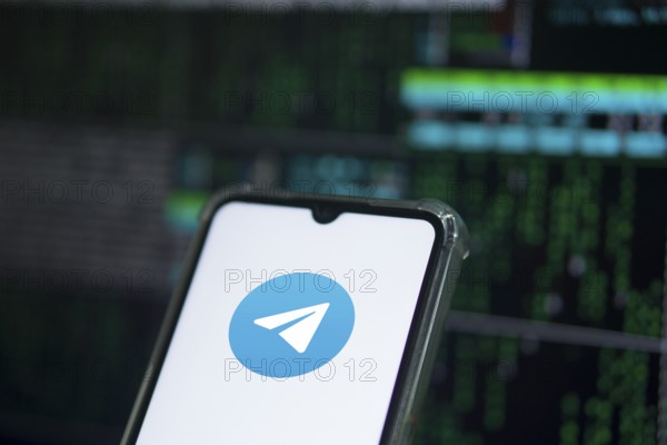The TELEGRAM app logo on the screen of a cell phone that a man is holding.