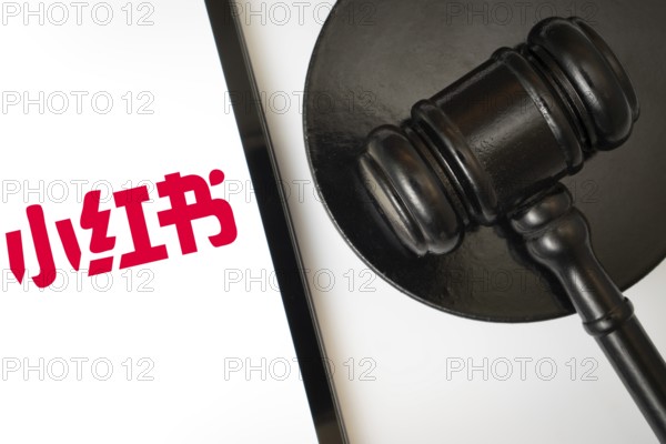 An iPad displays the RedNote (Xiaohongshu) logo alongside a judge's gavel