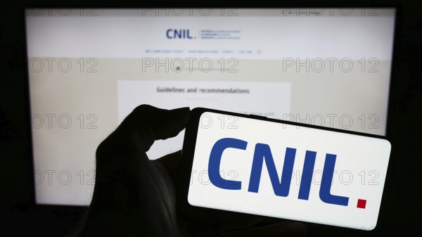 Stuttgart, Germany, 11-21-2023: Person holding mobile phone with logo of Commission Nationale de l'Informatique et des Libertés (CNIL) with web page. Focus on phone display
