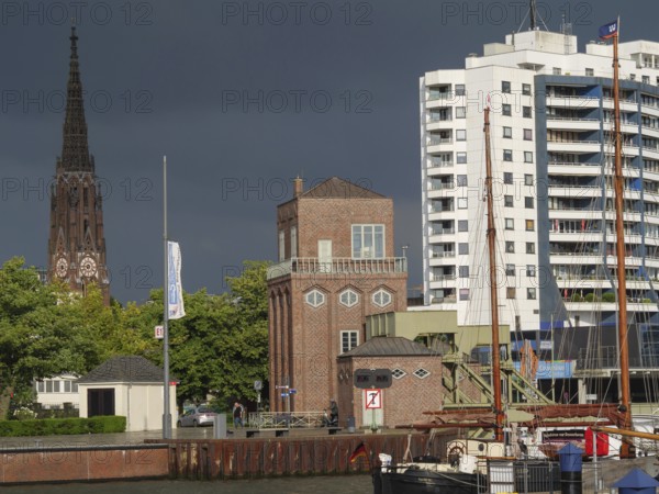 A cityscape with buildings, a church tower and ships in the harbour under a cloudy sky, bremerhaven, bremen, germany