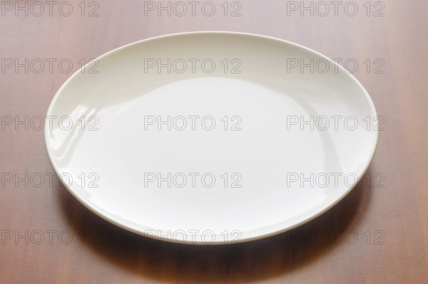 An empty white modern plate on a wooden table