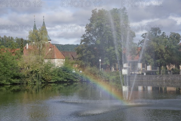 View from the Feuersee lake to the town church, rainbow, water feature, water fountain, Swabian-Franconian Forest nature park Park, Murrtal, Murr, Murrhardt, Baden-Württembergm, Germany