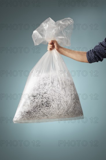 Man holding a transparent plastic bag with shredded paper