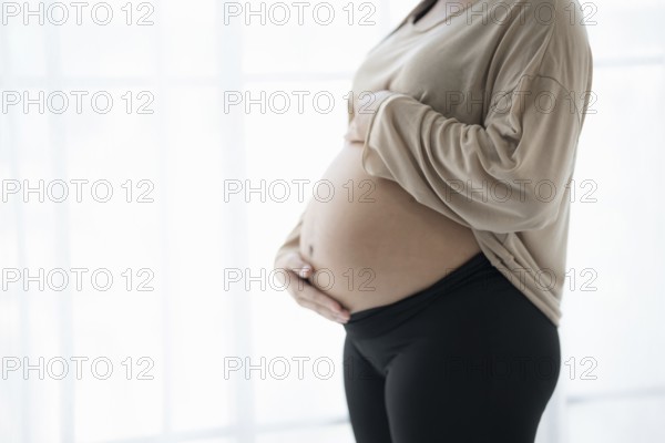 Pregnant woman holds hands on belly touching her baby caring about her health Beautiful happy pregnant woman tender mood photo of pregnancy