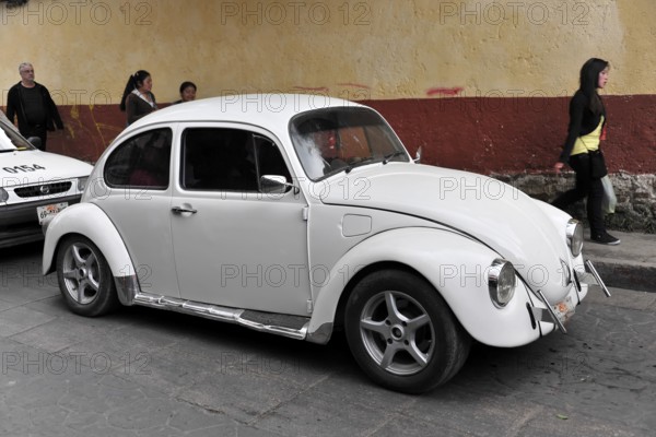 San Christobal de las Casas, Mexico, Central America, White VW Beetle classic model parked on a busy street, people in the background