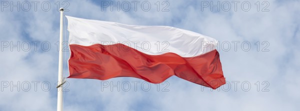 Flag of Poland waving at wind against beautiful blue sky. Polish flag White and red flutters on blue sky. National flag of Poland flapping on flagpole with sky behind