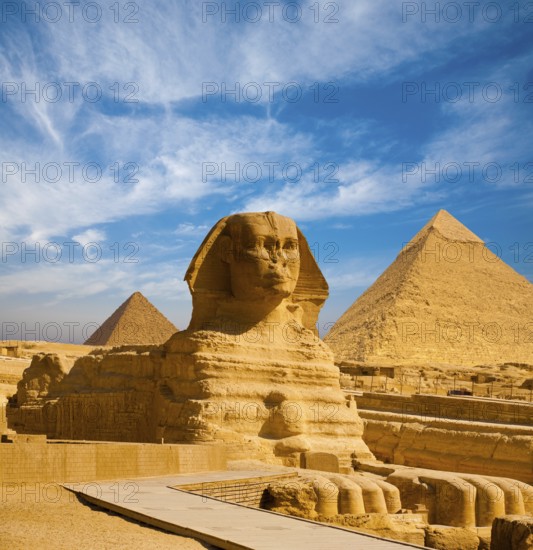 Full profile of Great Sphinx including pyramids of Menkaure and Khafre in the background on a clear sunny, blue sky day in Giza, Cairo, Egypt with no people
