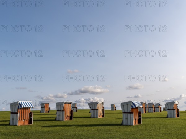 White beach chairs on a meadow and blue sky with clouds in the background, along the coast of the Unesco World Heritage Wadden Sea, Büsum, North Sea, North Frisia, Schleswig-Holstein, Germany