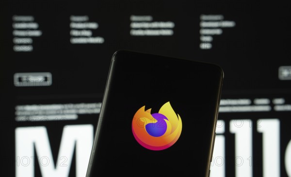 Dhaka, Bangladesh- 08 March 2025: mozilla firefox logo is displayed on a smartphone screen, with the mozilla firefox website visible on a computer screen in the background
