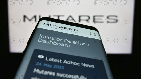 Stuttgart, Germany, 06-24-2023: Mobile phone with webpage of German investment company Mutares SE Co. KGaA on screen in front of logo. Focus on top-left of phone display