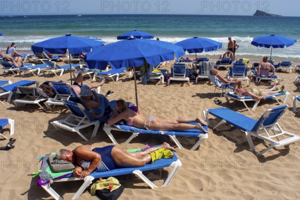 Holidaymakers sunbathe on Levante beach in Benidorm, Alicante province, Spain