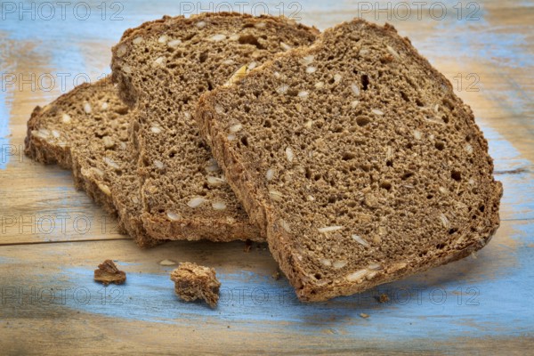 Slices of organic, whole grain, dark rye bread on painted wooden cutting board