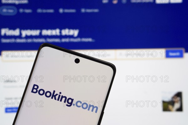 Booking.com logo is displayed on a smartphone screen, with the booking.com website visible on a computer screen in the background