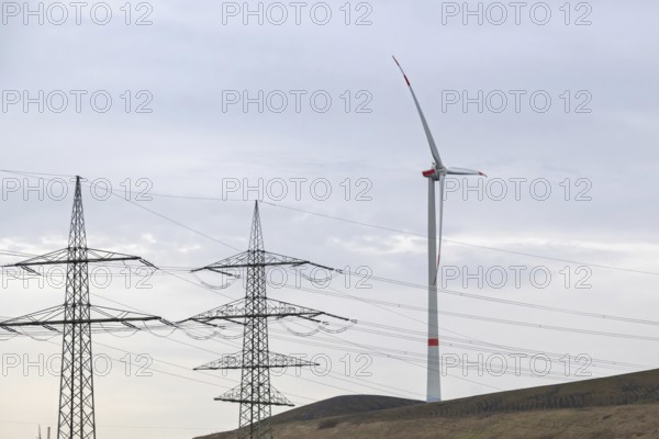 High-voltage pylons with wind turbine in german industrial landscape