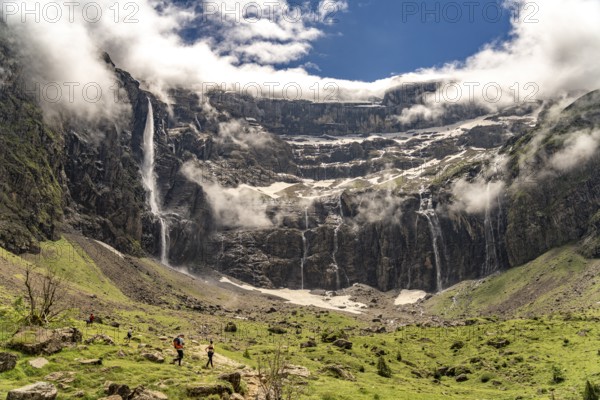 Hikers in the cloudy Cirque de Gavarnie basin, UNESCO World Heritage Site in the Pyrenees National Park near Gavarnie-Gèdre, France