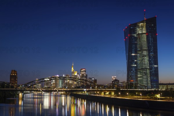 The European Central Bank (ECB) and the Frankfurt banking skyline are reflected in the calm waters of the Main at blue hour, Osthafen, Frankfurt am Main, Hesse, Germany