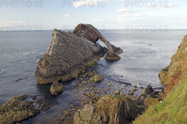 Rocky island by the sea with gentle waves surrounded by a clear sky, Bow Fiddle Rock, Aberdeenshire, Buckie, Scotland, United Kingdom