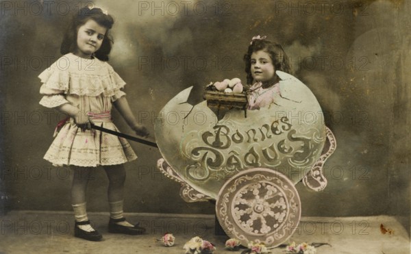 Child sitting in large egg, 1930s, Two girls in a vintage Easter photo with flowers and decoration, Historical photo