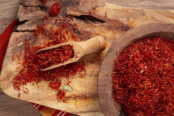 Spice saffron threads, in a wooden bowl, on a wooden table, top view, close-up