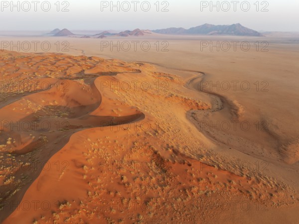 Sand dunes and isolated mountain ridges at the edge of the Namib Desert. Aerial view. Drone shot. Namibia