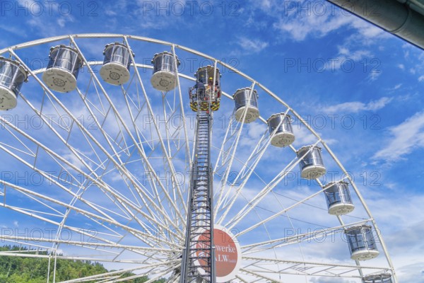 View of a high Ferris wheel with many baskets in front of a cloudy blue sky, fire brigade exercise for gondola rescue Ferris wheel, Calw, Germany